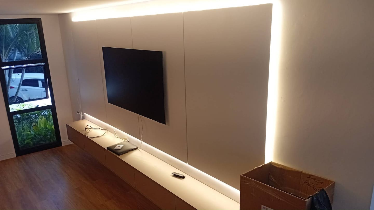 Vista em perspectiva de painel de TV iluminado com rack suspenso que percorre toda a parede da sala