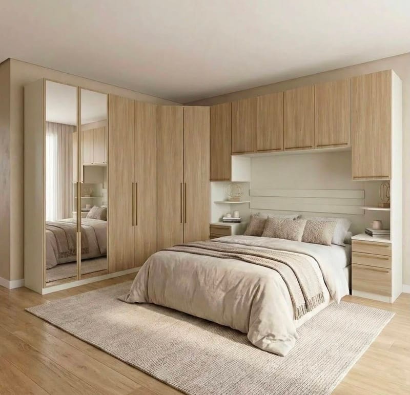 Quarto planejado em tom amadeirado claro, com guarda-roupa de portas espelhadas, cabeceira embutida, criados-mudos suspensos e armário aéreo sobre a cama